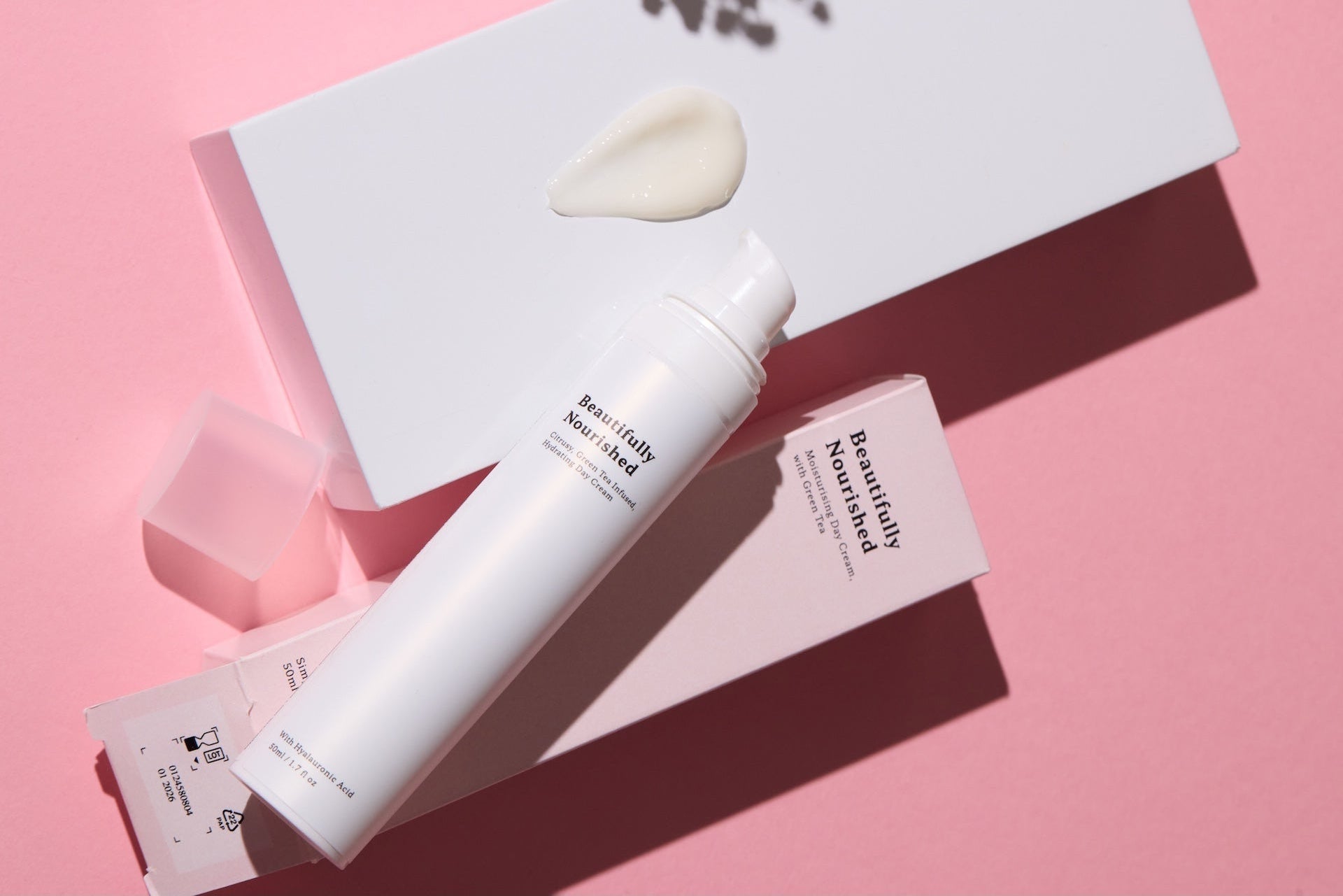 Skincare product with green tea and packaging on a pink background