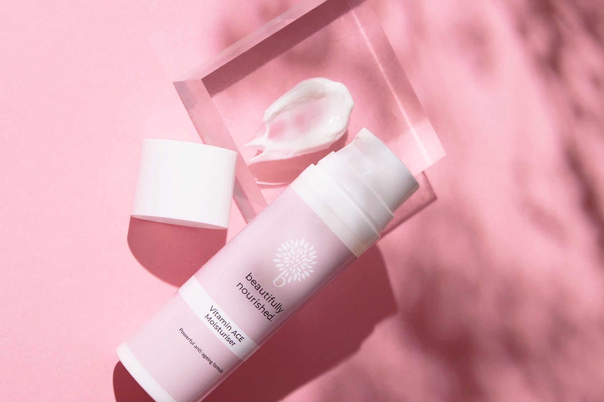 anti ageing vitamin ace moisturiser by beautifully nourished on pink background with cream texture visible